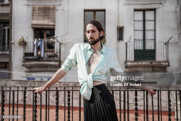 tradition and modernity: pretty non binary trans person with beard wearing a dark skirt posing in a traditional village - jupe stock-fotos und bilder