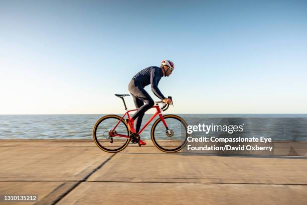 cyclist on path by sea - cicloturismo stockfoto's en -beelden