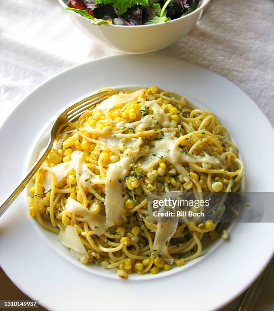 plate of spaghetti with corn, sage and shaved parmesan cheese that melts on the warm pasta - salad in the background - shaved parmesan stock pictures, royalty-free photos & images