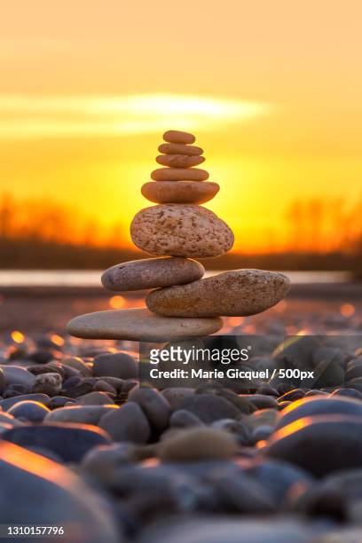 close-up of stacked pebbles at beach against sky during sunset,france - zen stone stock pictures, royalty-free photos & images