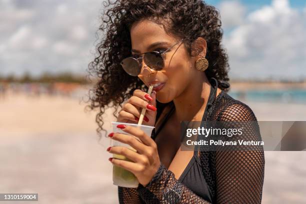 woman drinking tropical cocktail on the beach - caipirinha stock pictures, royalty-free photos & images