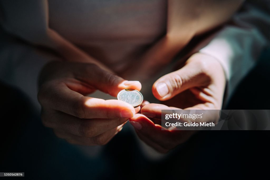 Woman holding a one euro coin with both hands.