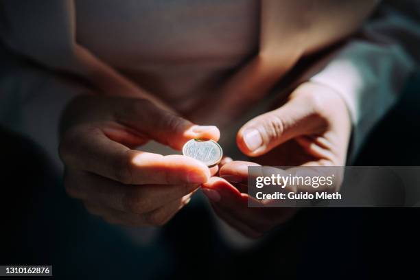 woman holding a one euro coin with both hands. - 硬貨 ストックフォトと画像