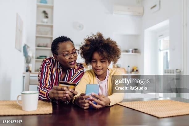 mujer mayor afroamericana y su nieta haciendo una compra en línea en casa - cuenta de banco fotografías e imágenes de stock