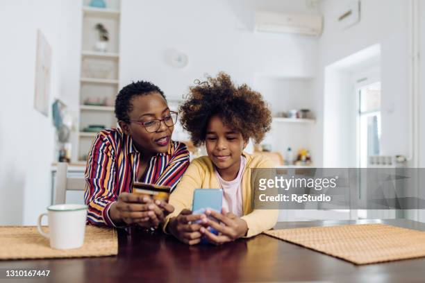 mulher idosa afro-americana e sua neta fazendo uma compra online em casa - conta bancária - fotografias e filmes do acervo