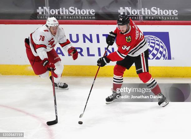 Carl Soderberg of the Chicago Blackhawks passes against Brady Skjei of the Carolina Hurricanes at the United Center on March 30, 2021 in Chicago,...