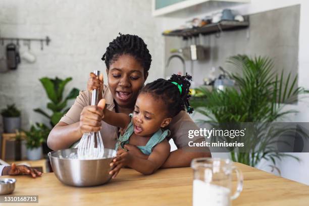 glückliche mutter und tochter bereiten schlagsahne in einer küche - black mother and child cooking stock-fotos und bilder