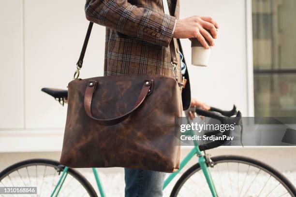 close-up van een onherkenbare zakenman met een kop koffie en zijn fiets - attaché stockfoto's en -beelden