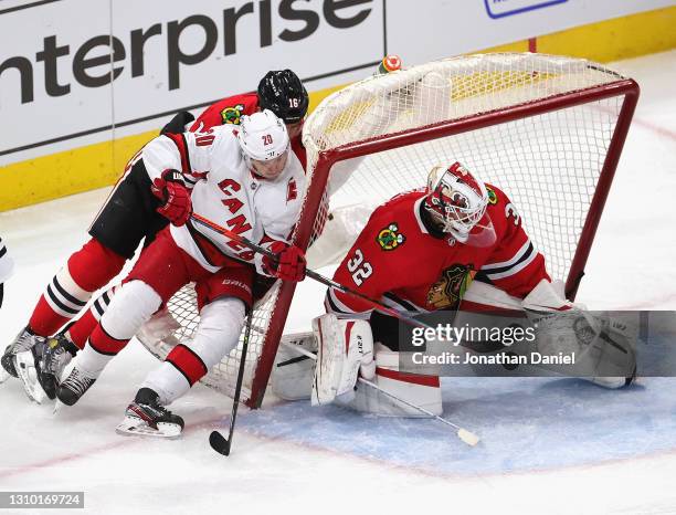 Kevin Lankinen of the Chicago Blackhawks makes a save as Sebastian Aho of the Carolina Hurricanes and Nikita Zadorov knock over the net at the United...