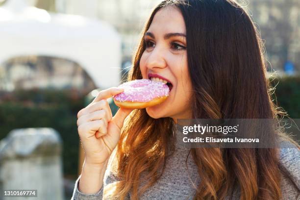 young woman eating a donut - mascar imagens e fotografias de stock