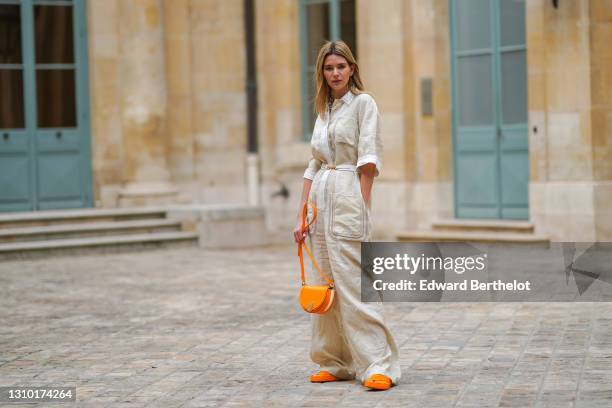Natalia Verza @mascarada.paris wears a white linen jumpsuit from Fendi with flare pants, a Fendi moon light orange bag, Fendi orange sandals, on...