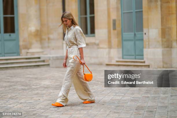 Natalia Verza @mascarada.paris wears a white linen jumpsuit from Fendi with flare pants, a Fendi moon light orange bag, Fendi orange sandals, on...