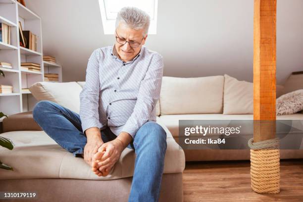 senior man suffering with foot cramp - rubbing stock pictures, royalty-free photos & images