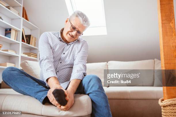 senior man suffering with foot cramp - rubbing stock pictures, royalty-free photos & images