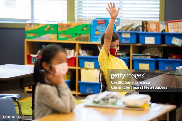 First grader Abel Olvera raises his hand in Mrs. Chavez's first grade classroom during the first day of partial in-person instruction at Garfield...