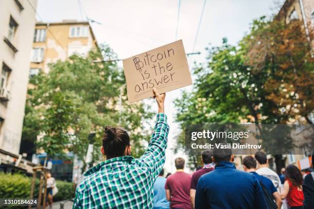 jonge mens die een affiche houdt die "bitcoin is het antwoord" zegt blokketen activistische voorraadfoto. - anti government stockfoto's en -beelden