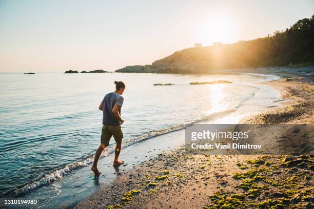 hombre corriendo en la playa al atardecer foto de archivo - delantero fotografías e imágenes de stock