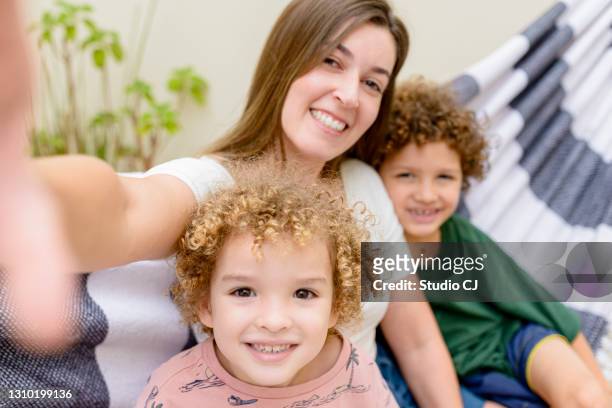 moeder die selfie met haar kinderen op de hangmat neemt - family law stockfoto's en -beelden