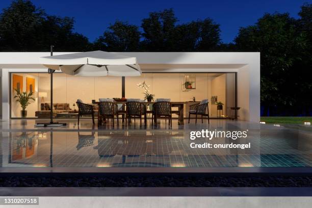 exterior of luxurious modern villa at night with swimming pool, patio table and chairs - patio lights stock pictures, royalty-free photos & images