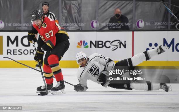 Shea Theodore of the Vegas Golden Knights skates with the puck as Andreas Athanasiou of the Los Angeles Kings falls down in the third period of their...