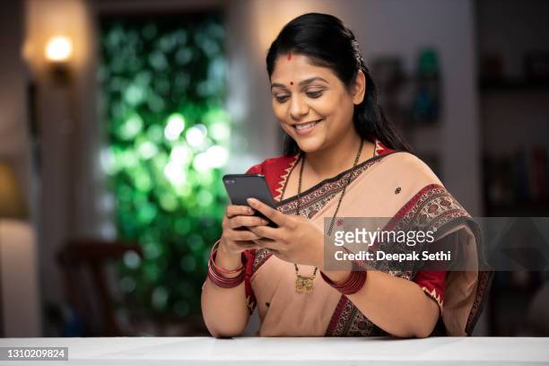 shot of a mid adult woman surfing the net on  mobile phone standing near window & balcony:- stock photo - mid adult women stock pictures, royalty-free photos & images