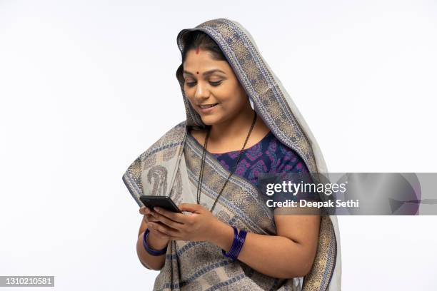 portrait of indian woman in sari using mobile phone standing isolated over white background:- stock photo - sari isolated stock pictures, royalty-free photos & images