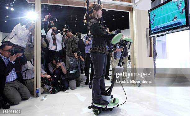 Model plays a video game as she demonstrates a "Balance Training Assist" robot at a Toyota Motor Corp. News conference showing new nursing and...