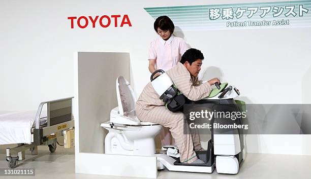 Models acting as a nurse, left, and patient demonstrate a "Patient Transfer Assist" robot at a Toyota Motor Corp. News conference showing new nursing...