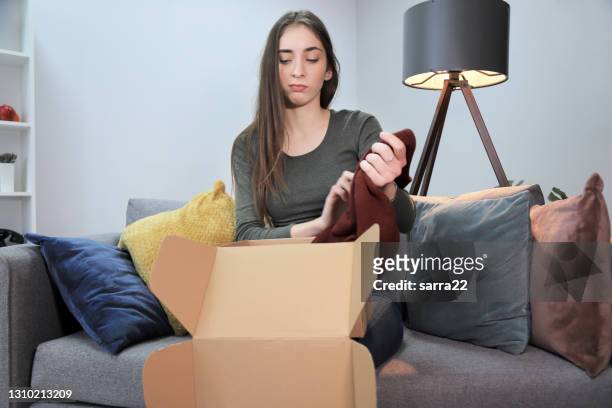 young woman unboxing a package and being unsatisfied with the product - damaged box stock pictures, royalty-free photos & images