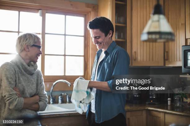 mature couple talking in kitchen at home - dish washing stock pictures, royalty-free photos & images