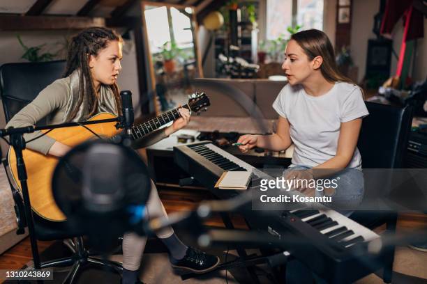 female songwriter and her colleague from the band an acoustic guitar player, having a meeting while working on the new album - songwriter stock pictures, royalty-free photos & images