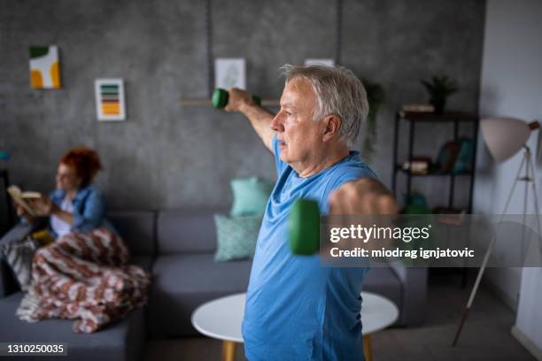 senior man watching exercise class on laptop and working out with dumbbells at home - hand weight stock pictures, royalty-free photos & images