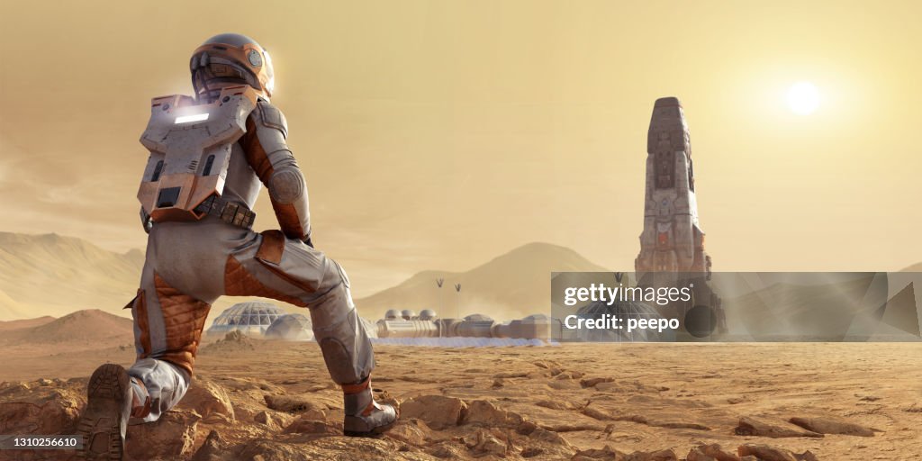 Astronaute sur Mars s’agenouillant et regardant l’établissement de camp de base et la fusée dans l’environnement rocheux de Mars