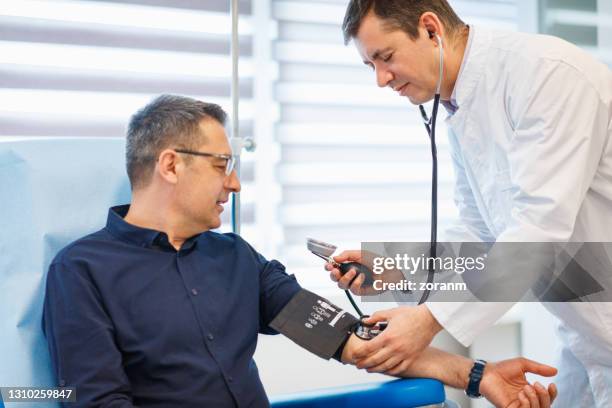 medico che controlla la pressione sanguigna a un paziente - sala di consultazione medica foto e immagini stock