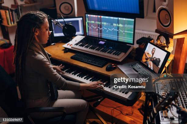 new wave female artist, playing the electric keyboard, while her female friend follow her on a acoustic guitar during their rehearsal via video call - virtual concert stock pictures, royalty-free photos & images