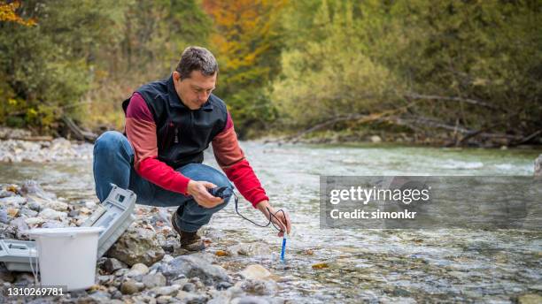 male biologist testing the oxygen levels in the river - experimental rock stock pictures, royalty-free photos & images