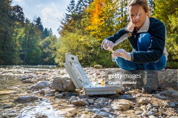 biologiste femelle ajoutant le reagent dans un flacon avec l’échantillon d’eau - prélèvement à tester photos et images de collection