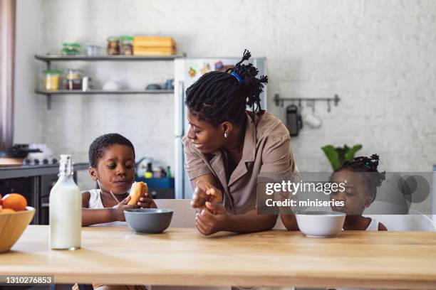 madre che dà colazione a figlia e figlio al tavolo della cucina - boy eating cereal foto e immagini stock