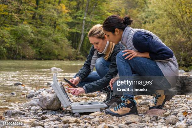 female biologists using digital device and digital tablet for water testing - biologist stock pictures, royalty-free photos & images