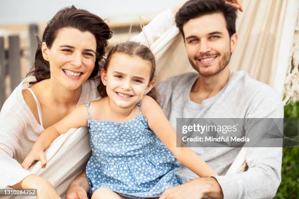 smiling family having fun while sitting in hammock - family with one child imagens e fotografias de stock
