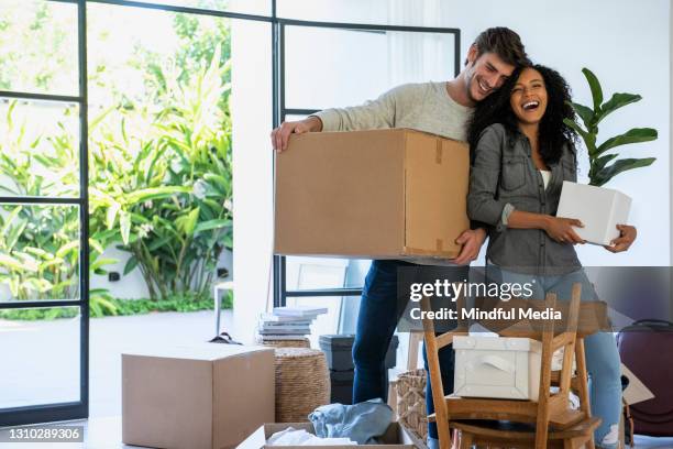 couple carrying cardboard box and pot plant in new house - new house stock pictures, royalty-free photos & images