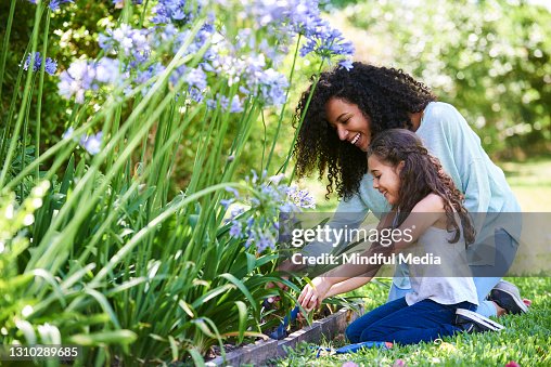 Mother and daughter planting flowers in garden