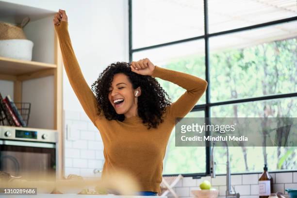 donna sorridente che ascolta musica e balla in cucina - tipo di danza foto e immagini stock