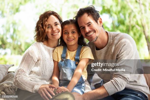 glimlachende ouders die met hun dochter op bank zitten - adoption stockfoto's en -beelden