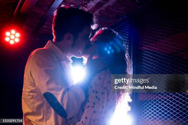 young couple kissing while dancing in nightclub - pecking stock pictures, royalty-free photos & images