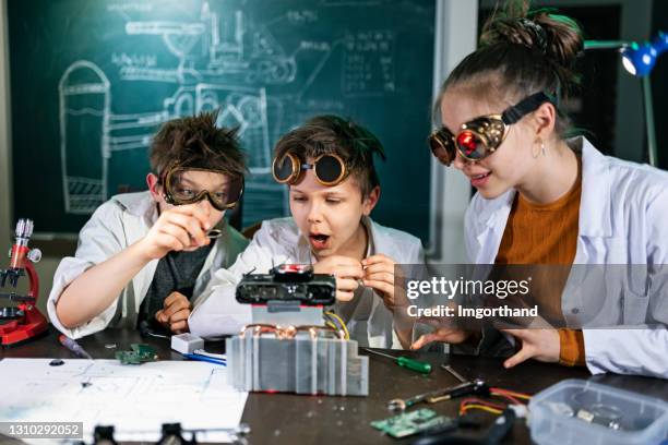 three young inventors are building a mysterious device - child inventor stock pictures, royalty-free photos & images