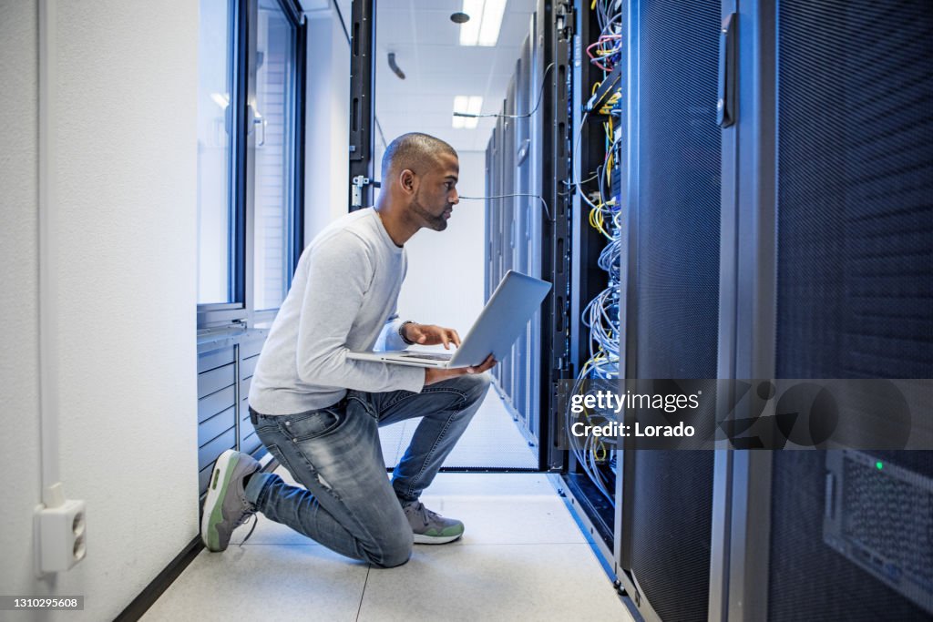 A black male server room technician working at business reopening