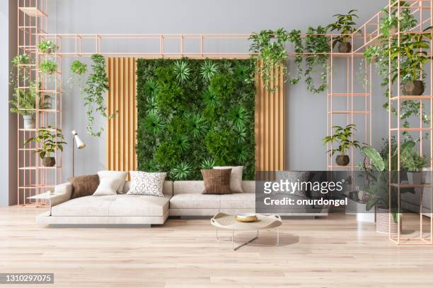 soggiorno verde con giardino verticale, piante della casa, divano di colore beige e pavimento in parquet - flora foto e immagini stock