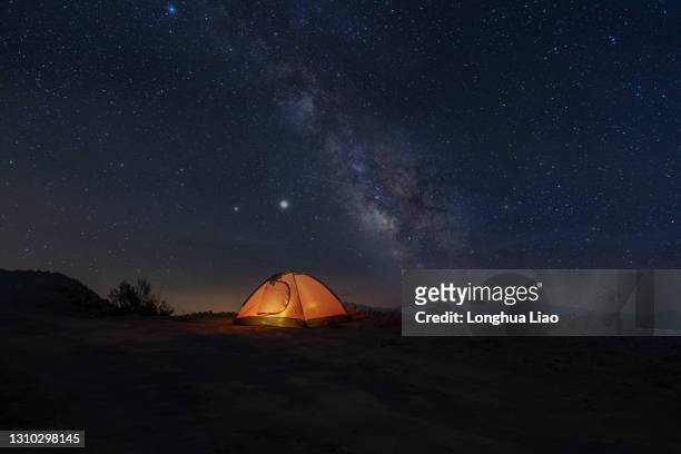 yellow tents lit up under the stars - campfire no people stock-fotos und bilder
