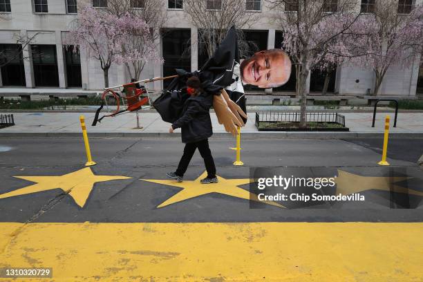 Demonstrator carries a large puppet of President Joe Biden away following a protest by indigenous environmental activists outside the White House...